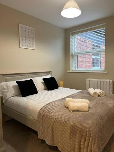 Well Equipped Apartment In Stoke on Trent في ستوك أون ترينت: غرفة نوم بسرير كبير عليها مناشف