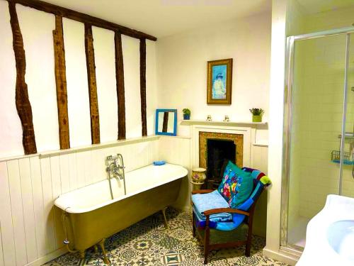 a bathroom with a bath tub and a chair at Castle Buildings Cottage2 in Llanrhaeadr-ym-Mochnant