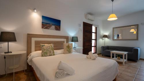 ein Schlafzimmer mit einem großen weißen Bett und einem Sofa in der Unterkunft Apartaments ES POU in Sant Ferran de Ses Roques