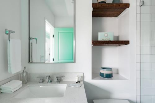 ein weißes Badezimmer mit einem Waschbecken und einem Spiegel in der Unterkunft Peace palace in Los Angeles