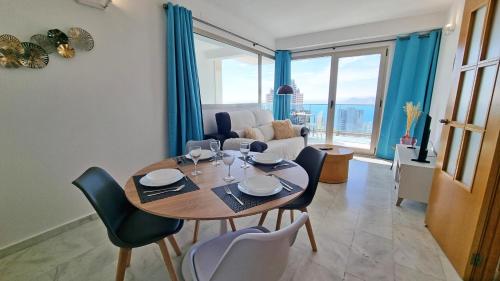 a dining room with a table and chairs and a couch at Terraza privada con impresionantes vistas al mar in Benidorm
