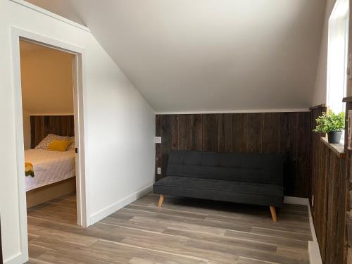 ein Schlafzimmer mit einem Bett und einem schwarzen Sofa in der Unterkunft Le Kamillō in Notre-Dame-Des-Bois