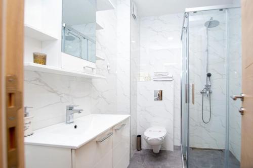 ein weißes Bad mit einer Dusche und einem WC in der Unterkunft Comfort apartment Becici by In Property in Becici