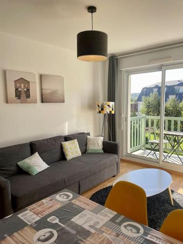 un salon avec un canapé et une table dans l'établissement Joli appartement avec parking et balcon, à Touques