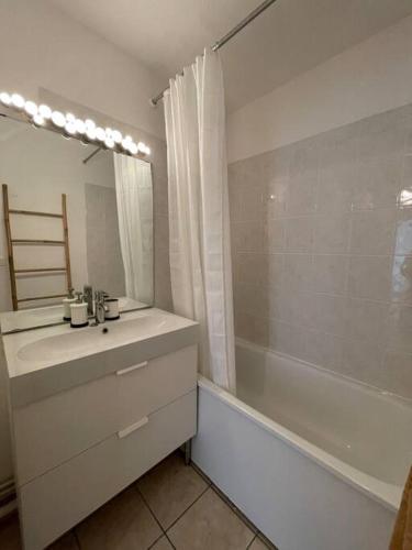 W łazience znajduje się umywalka, wanna i lustro. w obiekcie Joli appartement avec parking et balcon w mieście Touques