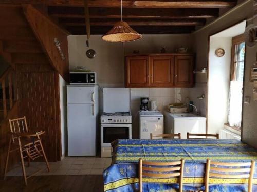 une cuisine avec des appareils blancs et une table avec des chaises dans l'établissement Maison au vert à la campagne - 5 personnes, à Saint-Nectaire