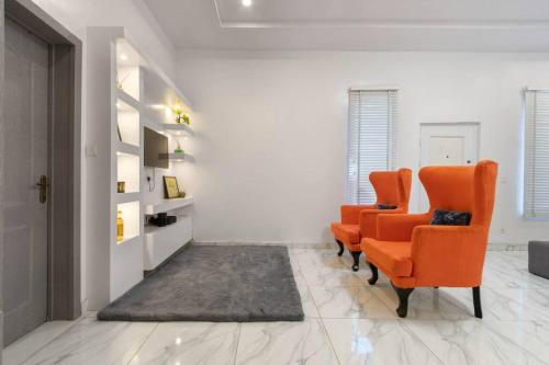 uma sala de estar com cadeiras laranja e um tapete em Skyfall em Lekki