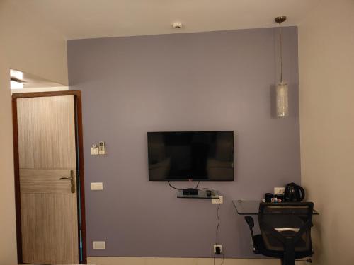 a room with a flat screen tv on a wall at Apollo Guest House in Mumbai