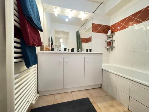 a bathroom with white cabinets and a tub and a sink at Résidence aux portes de Genève in Annemasse