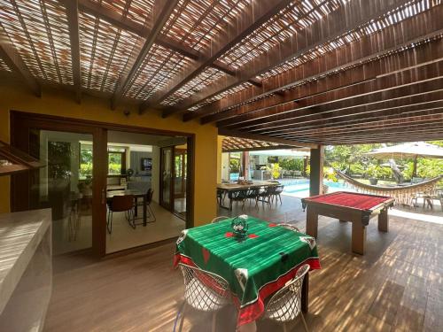 a living room with a green table and a patio at Sauipe House D10 - Mansão 6 suítes com luxo e conforto in Costa do Sauipe