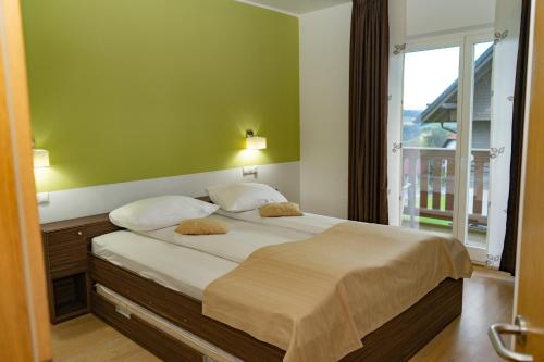 - une chambre avec un grand lit et une grande fenêtre dans l'établissement Apartmajska hiša Breza, à Ribnica na Pohorju