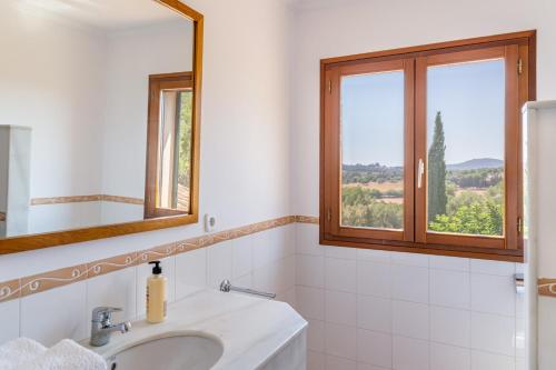 une salle de bain blanche avec un lavabo et deux fenêtres dans l'établissement Finca Porto Cristo - Es Bosquet, à Manacor