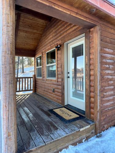 a front porch of a log cabin with a white door at The Lodge at Devils Tower in Devils Tower