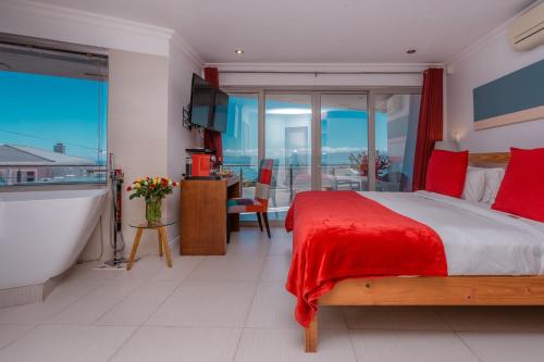 a bedroom with a bed and a bath tub and a bathroom at Sea Star Lodge in Gansbaai