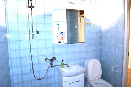 La salle de bains est pourvue de carrelage bleu, d'une douche et de toilettes. dans l'établissement Comfortable apartment near Helsinki airport, à Vantaa