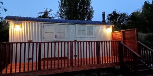 a small white cottage with a gate and lights at Woodpecker Shepherds Hut in Boston
