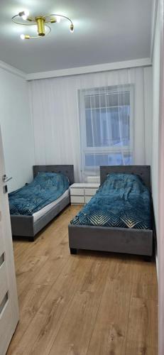 two beds in a room with wooden floors at Apartament KRYSTIAN in Suwałki