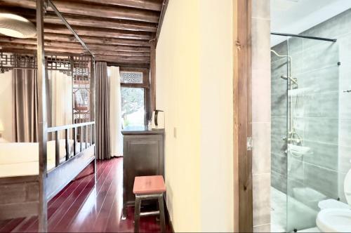 a bathroom with a glass shower with a stool in it at Qingxin Courtyard Art Guesthouse in Dali