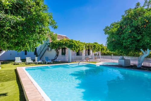 a swimming pool in a yard with chairs and trees at Huerta la Pimentada in Palma del Río