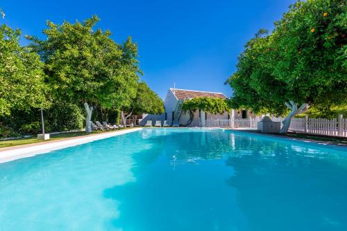 a large blue swimming pool in a yard with trees at Huerta la Pimentada in Palma del Río