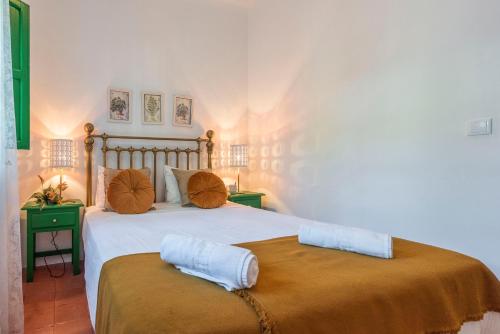 a bedroom with a large white bed with two pillows at Huerta la Pimentada in Palma del Río