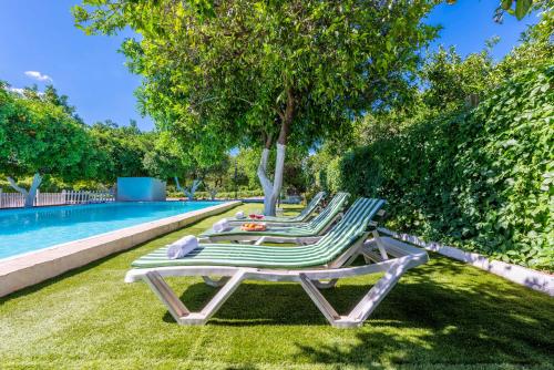 two lounge chairs and a table next to a swimming pool at Huerta la Pimentada in Palma del Río