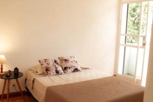 um quarto com uma cama com duas almofadas e uma janela em Apartamento Gutierrez 2 em Belo Horizonte