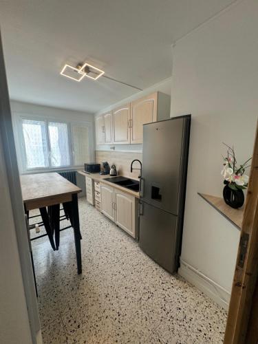 une cuisine avec un réfrigérateur et une table à l'intérieur dans l'établissement Appartement proche de la gare, à Alès