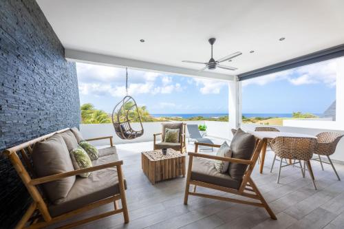ウィレムスタッドにあるThe Reef - Blue Bay Golf & Beach Resortの椅子とテーブルが置かれた海が見えるパティオ