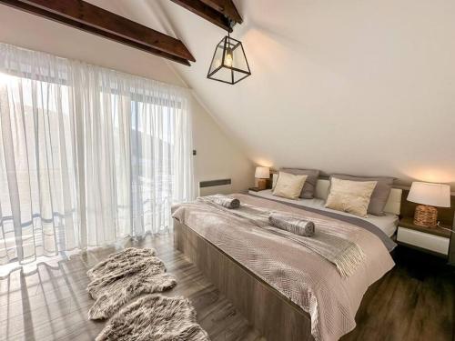 a bedroom with a large bed and a large window at Wellness Chalet in Mýto pod Ďumbierom