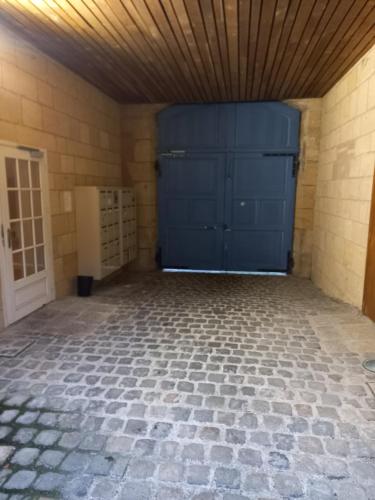 uma garagem com uma porta de garagem azul e piso em azulejo em le Fort de Bayle em Sedan