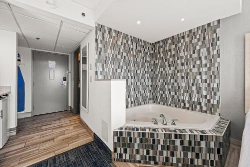 a bathroom with a tub and a tile wall at Hotel Monte Carlo Ocean City in Ocean City