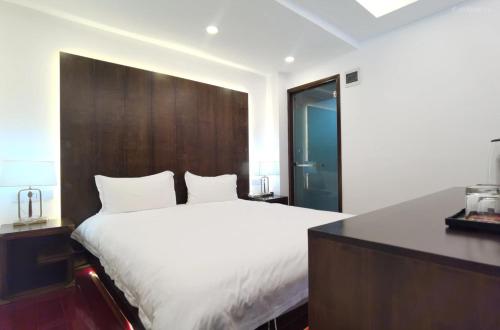 a bedroom with a white bed and a wooden headboard at Qingxin Courtyard Art Guesthouse in Dali