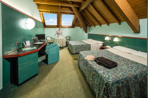 a hotel room with two beds and a desk at Hotel & Loisir Le Ruote in Roveleto