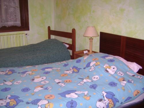 a bed with a blue blanket with animals on it at LES HIRONDELLES in Les Orres