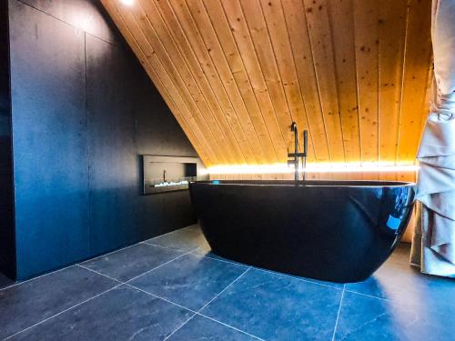 a bathroom with a bath tub with a wooden ceiling at RzepiskaView in Rzepiska