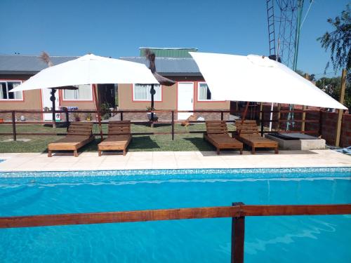 two white umbrellas and benches next to a pool at La Delia in Gualeguaychú