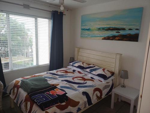 1 dormitorio con 1 cama con un edredón colorido en Laguna la crete 169 uvongo, en Margate