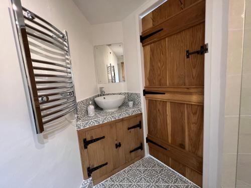 a bathroom with a sink and a wooden door at Fulmar Cottage in Mevagissey