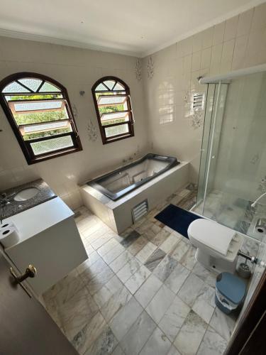 ein Badezimmer mit einer Badewanne, einem Waschbecken und einem WC in der Unterkunft Casa com piscina em Barra do Una in São Sebastião