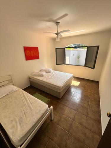 two beds in a room with a window at Casa com piscina em Barra do Una in São Sebastião