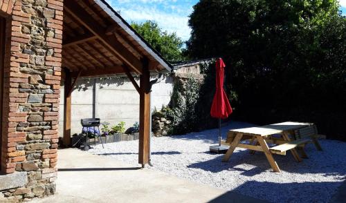 - une table de pique-nique et un parasol rouge à côté d'un bâtiment dans l'établissement Location Maison 4 / 8 personnes en Côtes D'Armor, à Étables