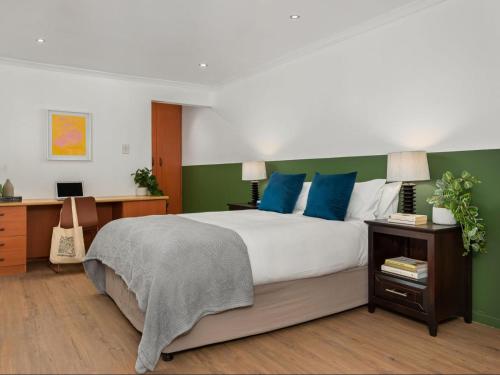 a bedroom with a large bed with blue and green walls at Neighbourgood Ravenscraig in Cape Town
