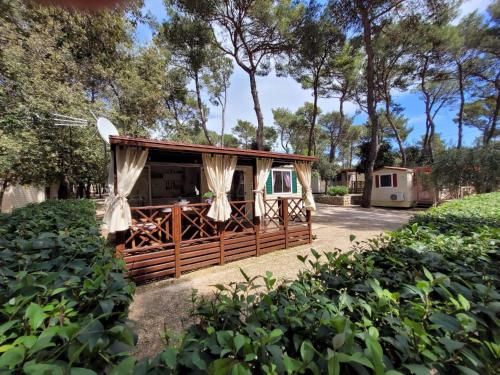 eine kleine Hütte mit einem Zaun und Bäumen in der Unterkunft Lucija Mobile Home in Biograd na Moru