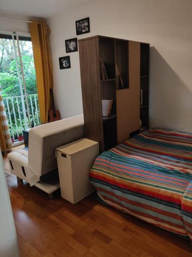 - une chambre avec un lit, une chaise et une étagère dans l'établissement Cozy Gateaway, à Neuilly-sur-Seine