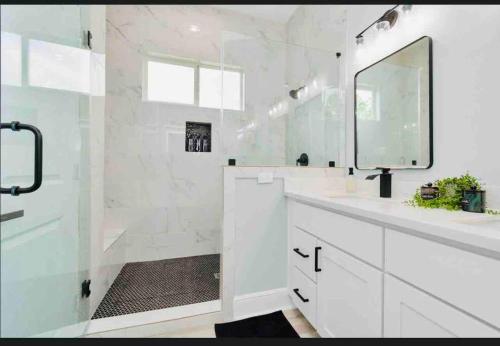 a white bathroom with a sink and a mirror at CAMP OUT - Big Backyard - 5mins To Downtown in Houston
