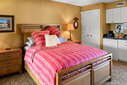 a bedroom with a large bed with a pink comforter at Studio Boutique Resort Across from Beach in Kihei