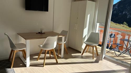 een eetkamer met een tafel en stoelen en een televisie bij Auron Joli appartement in Auron