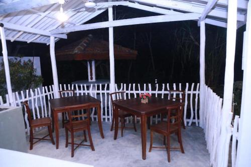 two wooden tables and chairs under a white pergola at Natural Lake Down South in Kahanda
