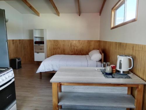 1 dormitorio con 1 cama y 1 mesa en una habitación en Ruta 7, en Coyhaique